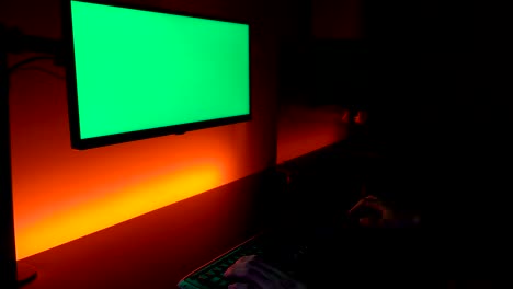 Grüner-Bildschirm:-Kaukasische-Hände-Auf-Dunkler-Tastatur-Mit-Monitor-über-Gelben-Und-Orangefarbenen-Lichtern
