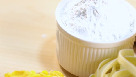 a detailed view of cornflakes, pasta, and flour on a wooden surface with bright lighting
