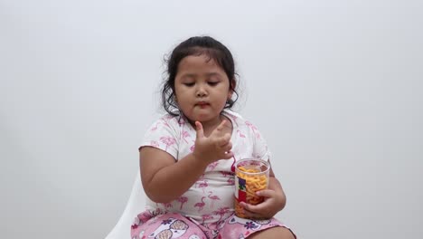 adorable niña asiática sentada mientras come un bocadillo