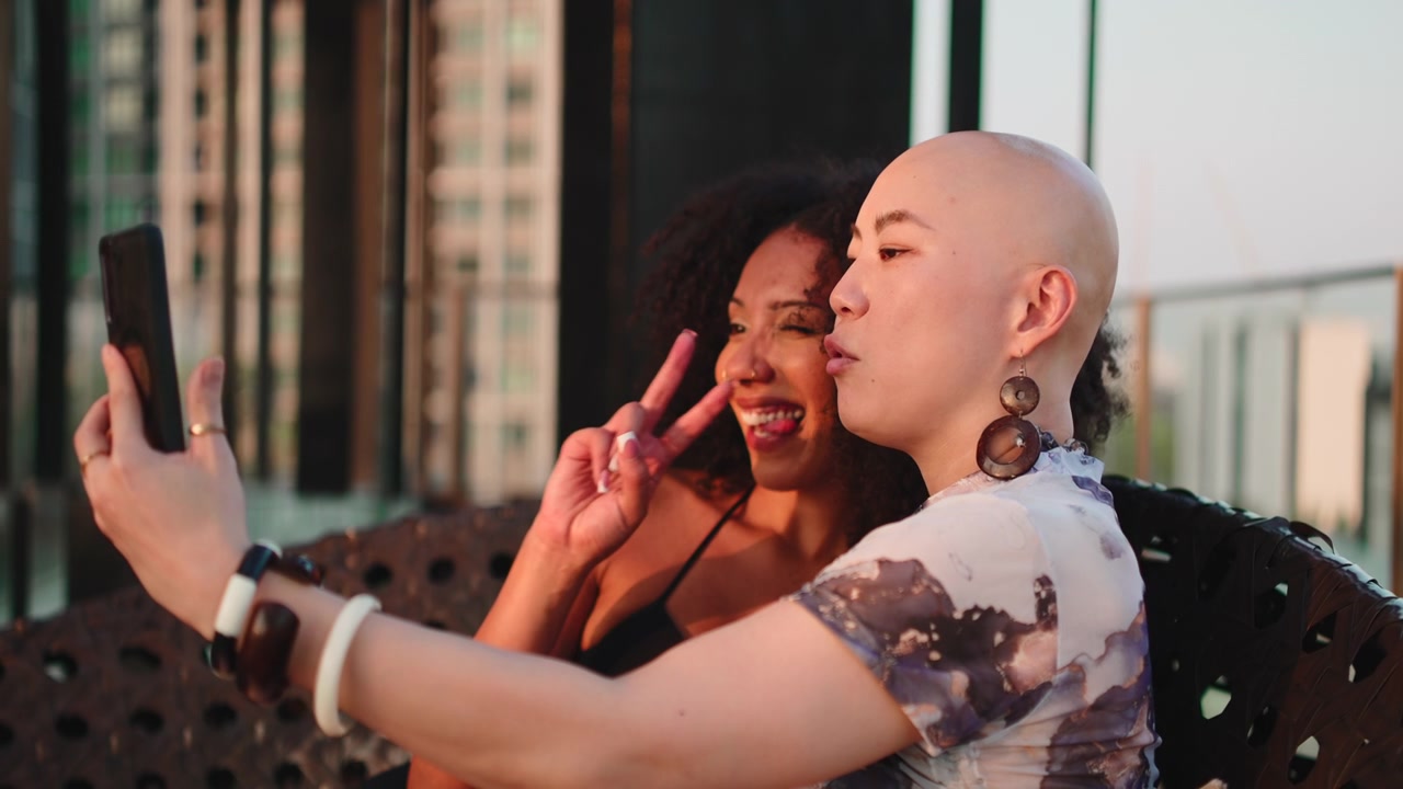 Two Friends Taking a Selfie on a Rooftop at Sunset