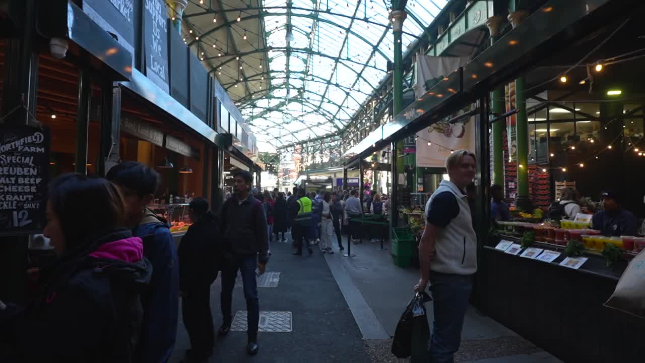 Bustling day at London's Borough Market with people browsing shops under a glass roof