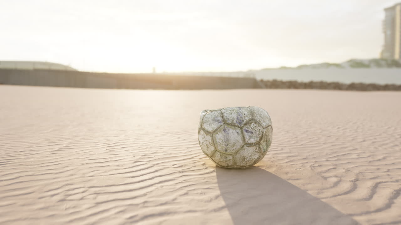 해가 지는 해변에 있는 오래된 축구공