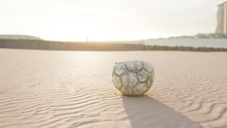 old soccer ball on a beach at sunset