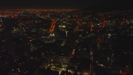 Atemberaubende-Panoramaaufnahmen-Aus-Der-Luft-Von-Nachtstädten.-Fliegen-Sie-über-Gebäuden-Im-Stadtbezirk.-Kapstadt,-Süd-Afrika