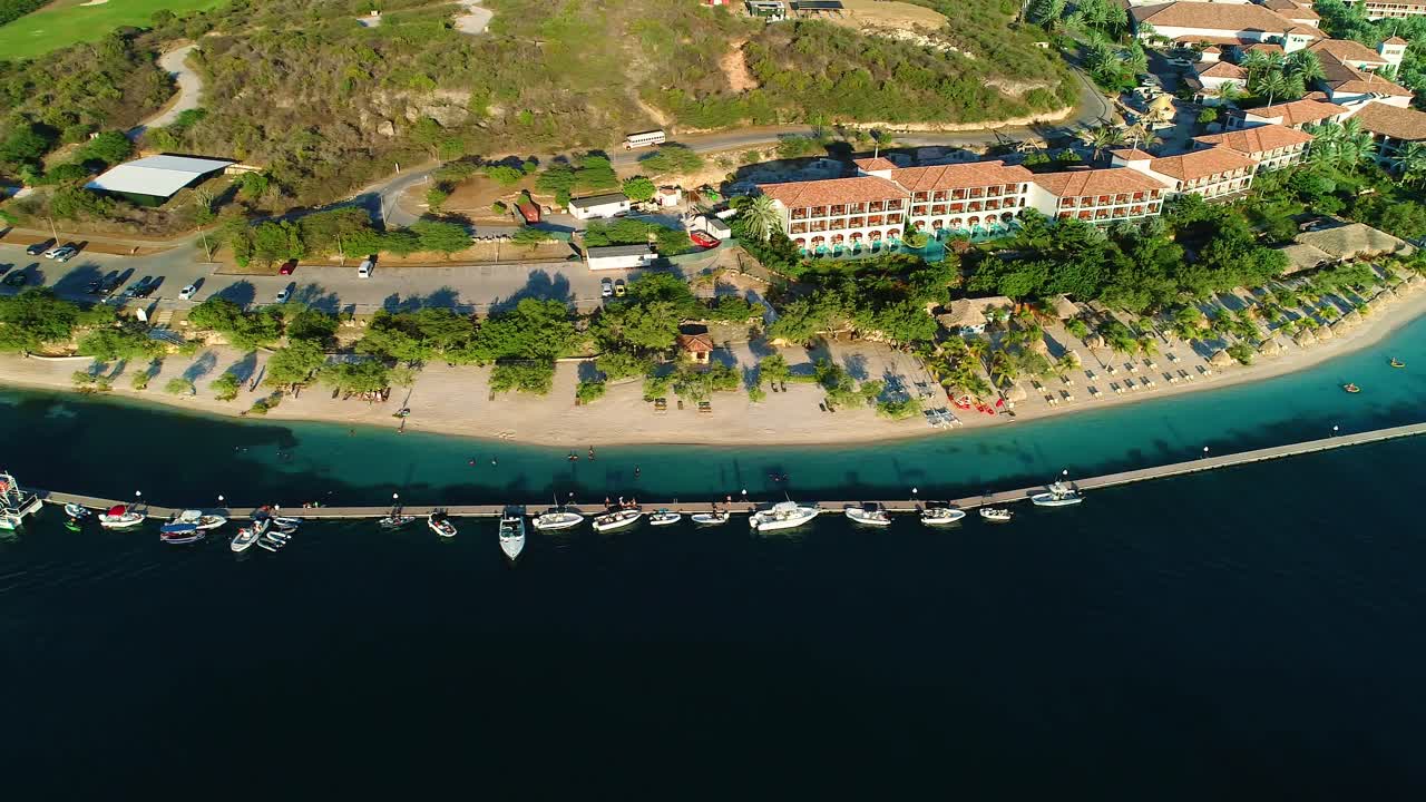 Bird's eye view pan, sandals resort sandy barbara beach and boat pier dock, aerial drone