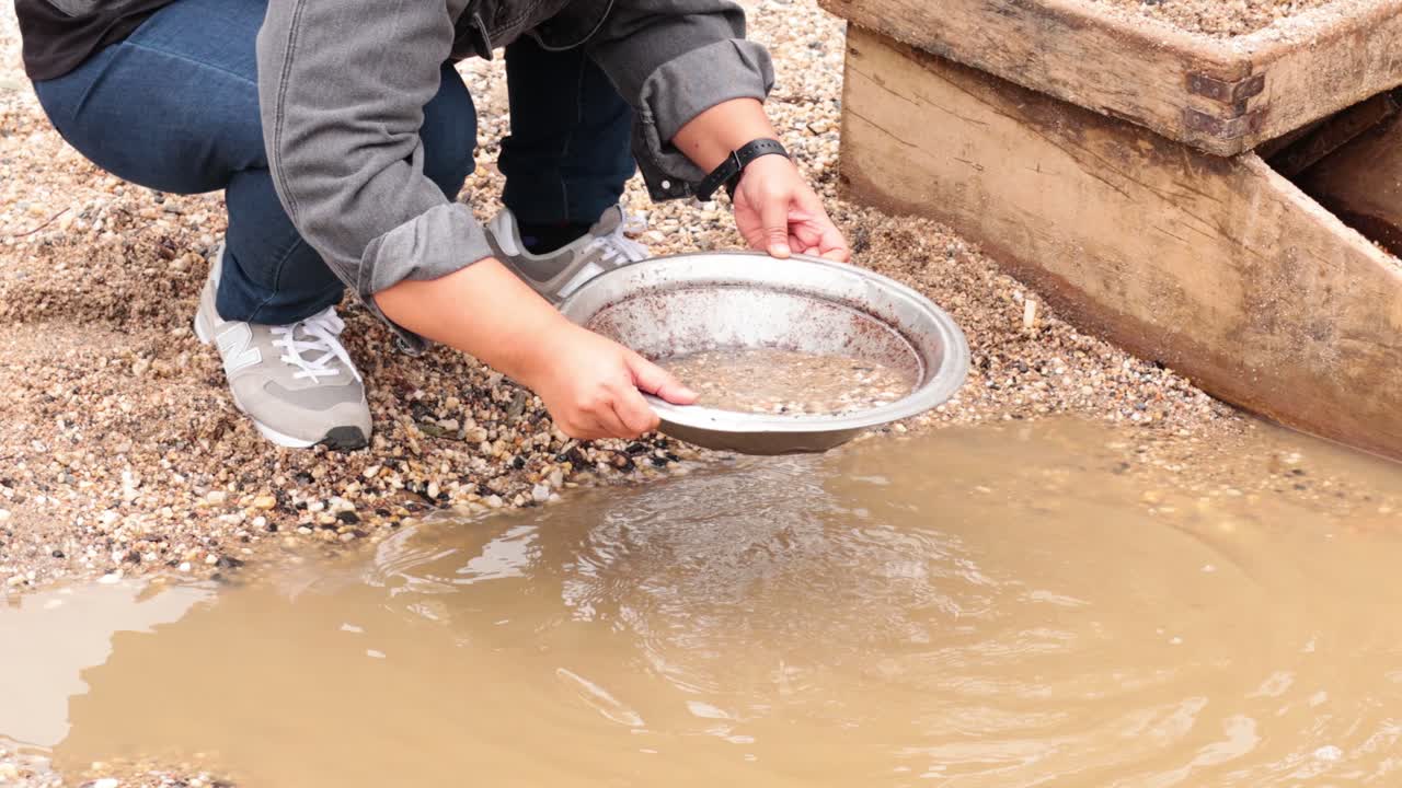 persona buscando oro en aguas fangosas