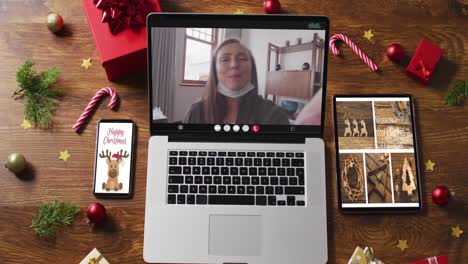 mujer mayor caucásica feliz en videollamada, con teléfono inteligente, tableta y decoraciones navideñas
