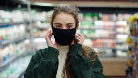 woman shopper makes purchases during the coronavirus epidemic, putting on her protective mask