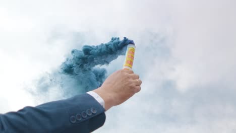 man in suit holding hand flare with blue smoke