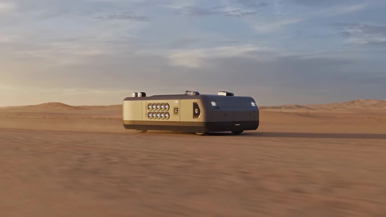 Un elegante rimorchio si muove attraverso la sabbia aperta del deserto sotto un cielo al tramonto tenue, con orizzonte basso, dune distanti e movimento sfocato in primo piano che suggerisce un viaggio costante.