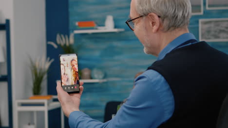 anciano remoto haciendo una llamada de video con su sobrino usando un teléfono inteligente