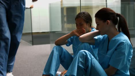 sad nurses sitting on corridor