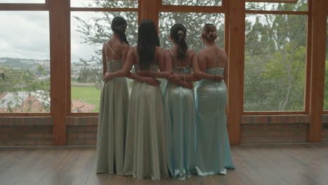 a cheerful clip where four bridesmaids, standing with their backs to each other, take a selfie in front of a large window showing a beautiful natural landscape.