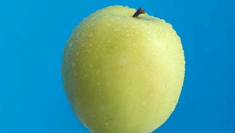 An Apple with Water Drops on a Bright Blue . An apple with water drops on a bright blue . Subject shooting of a juicy and useful fruit