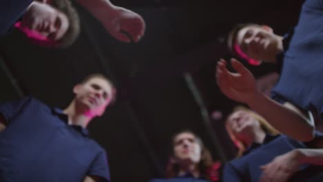 desde abajo, una foto de cinco jugadores profesionales de deportes electrónicos que se unen en símbolo de unidad y trabajo en equipo exitoso