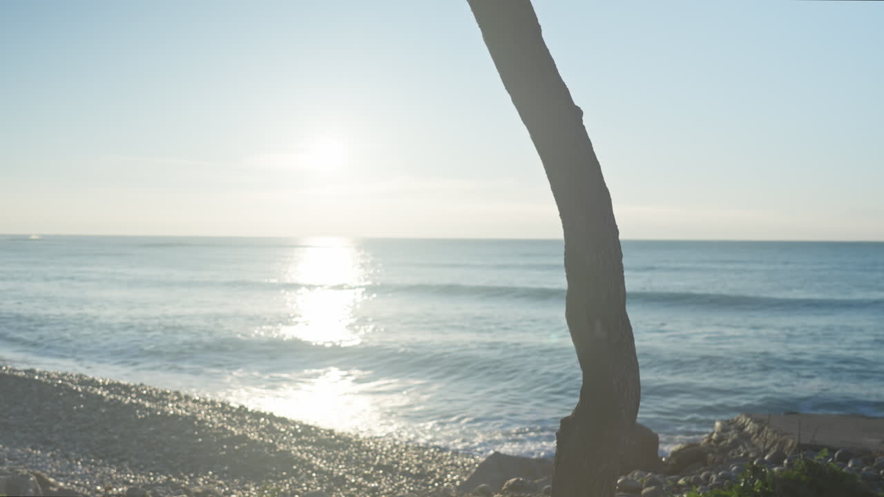 남자는 자전거를 타고 화창한 아침 바위 해변을 따라 걸어간다