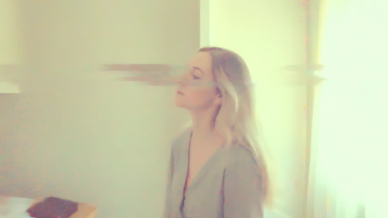 Donna bianca in una stanza illuminata dal sole si ferma con gli occhi chiusi, sovrapposizione onirica di glitch vintage, texture a grana calda, morbida