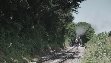 locomotora de vapor vintage acercándose de frente con una cabeza llena de vapor