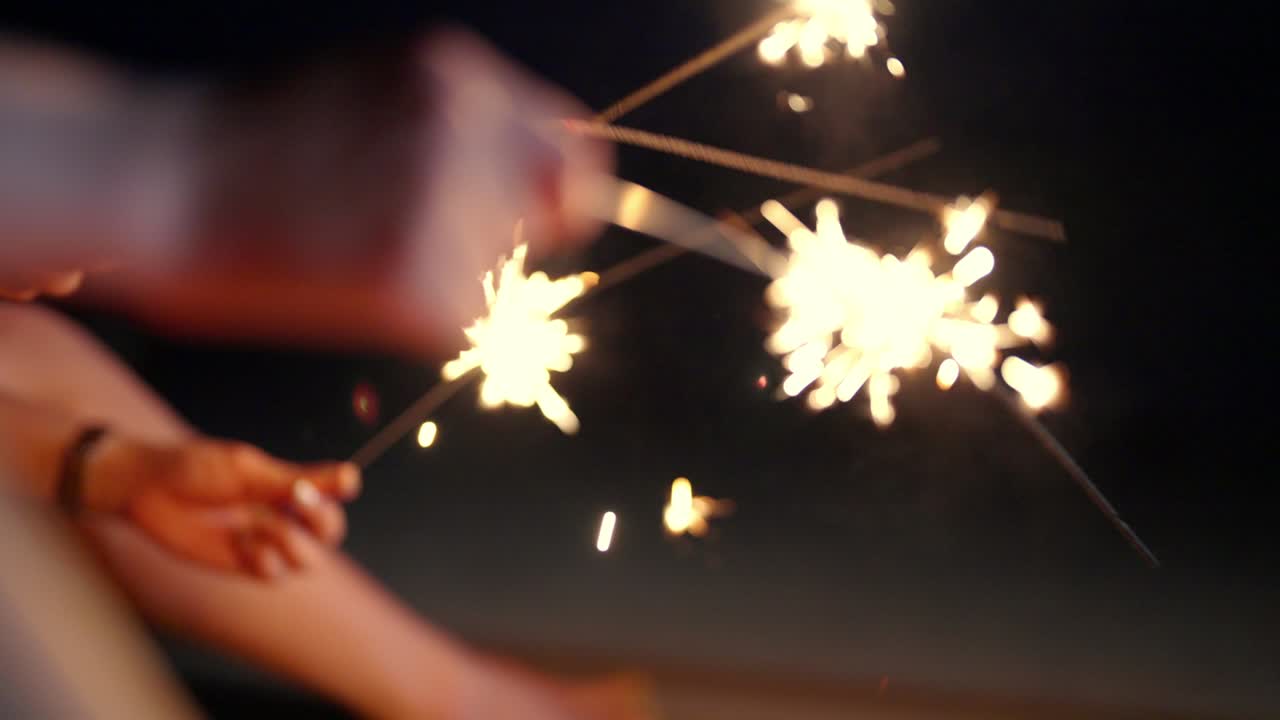 4K Group of Asian woman playing sparklers together on tropical island beach in summer night.