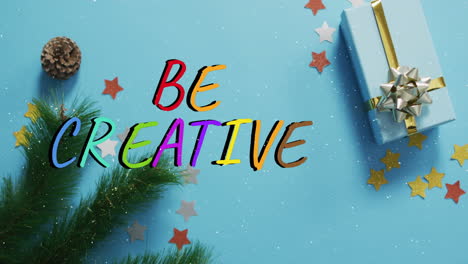 animation of snow falling over be creative text banner against gifts and decorations on blue surface