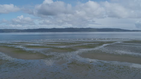 aerial drone footage flying across the wetlands of the beach of dumas bay towards the waves of the water.