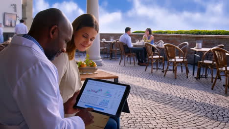healthcare professional showing data on a tablet to a woman in an outdoor cafe setting