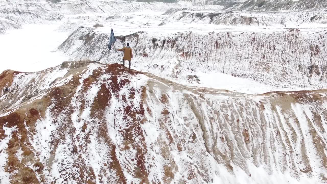 persona sosteniendo una bandera en una colina de cantera nevada