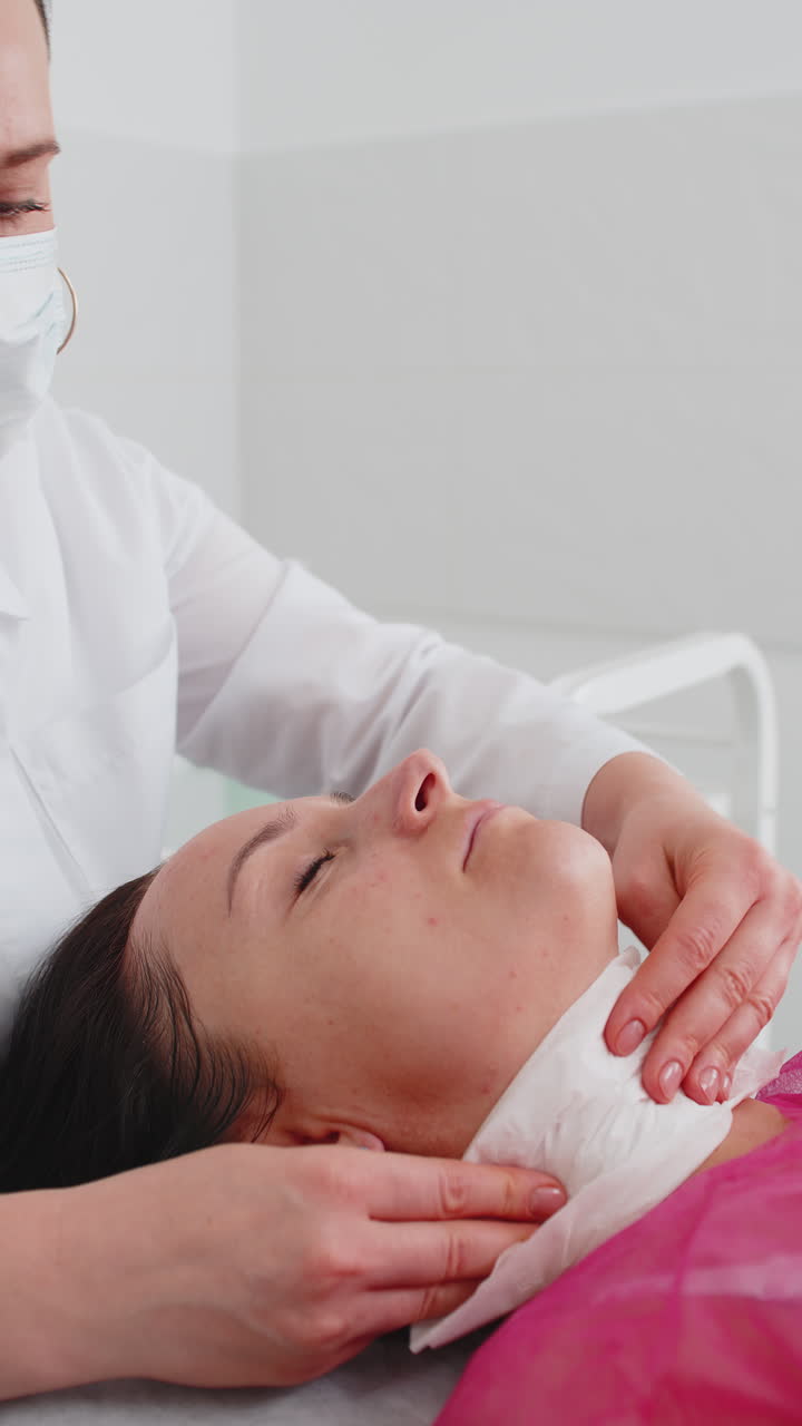 Cosmetologist doctor wipes woman face and neck cleaning procedure with paper wipes in beauty clinic