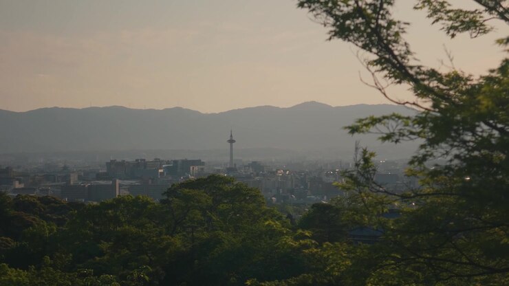 Una vista panoramica velata si affaccia su colline distanti e una cittadina nella valle in Giappone.