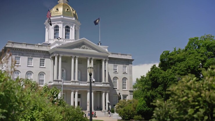 Panoramica verticale cinematografica dal marciapiede che conduce verso la New Hampshire State House, rivelando lo storico edificio del Campidoglio a Concord, New Hampshire, in una soleggiata giornata estiva.