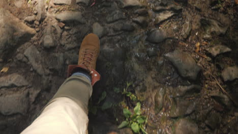 a man in trekking boots walks along a slippery stony path in the forest first-person video hiking an