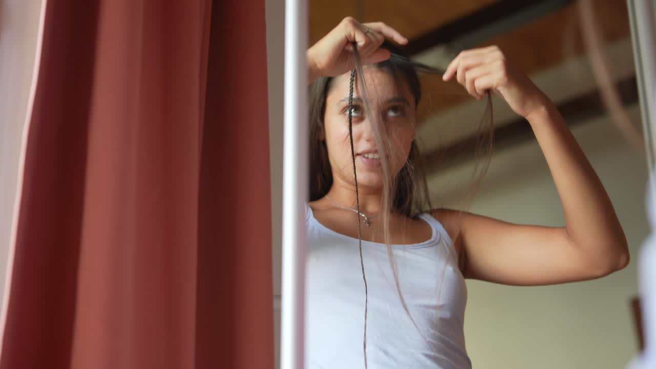 Teenage Girl Styling Her Hair in Front of a Mirror