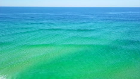 aerial: drone shot flying out to sea over a turquoise coloured ocean