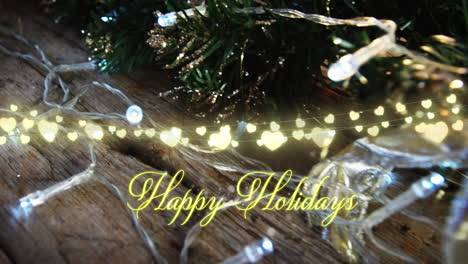 animation of text, happy holidays, in yellow, over string lights and decorated christmas tree