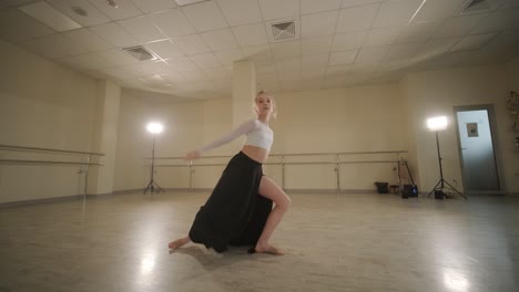 a group of young ballet students in black dancewear practicing positions in a spacious ballet studio with wooden flooring and wall-mounted barres. focused expressions and synchronized movements.