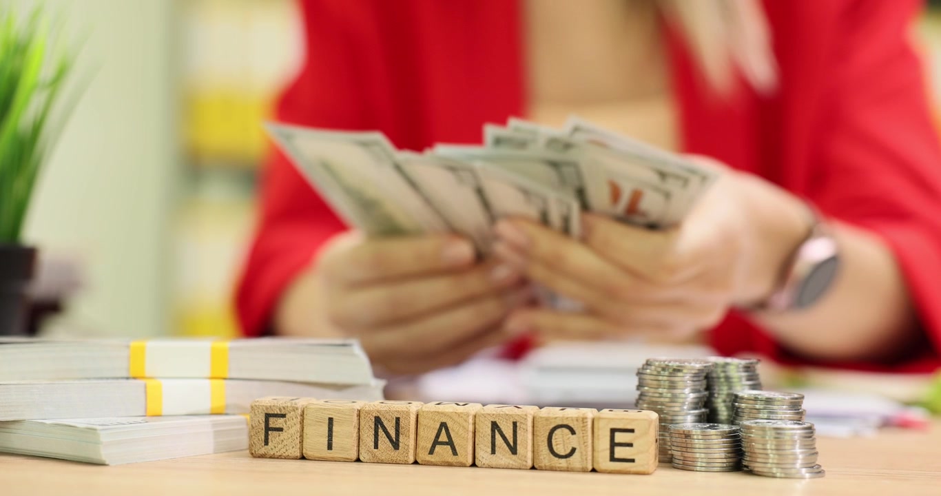 Woman counts cash at workplace with word finance from cubes