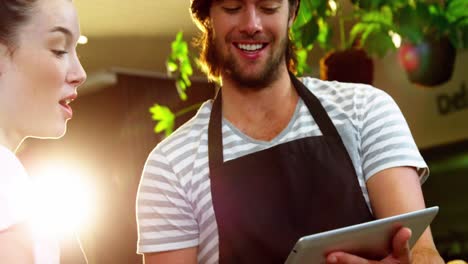 Waiter-and-waitress-discussing-over-digital-tablet