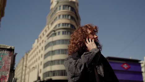 beautiful curly european woman answering phone in madrid city center