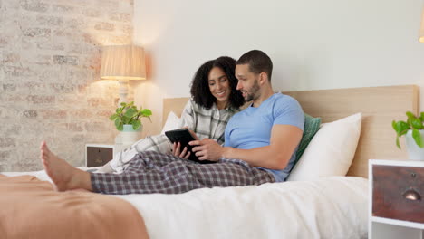 Couple,-tablet-and-relax-in-home-bedroom