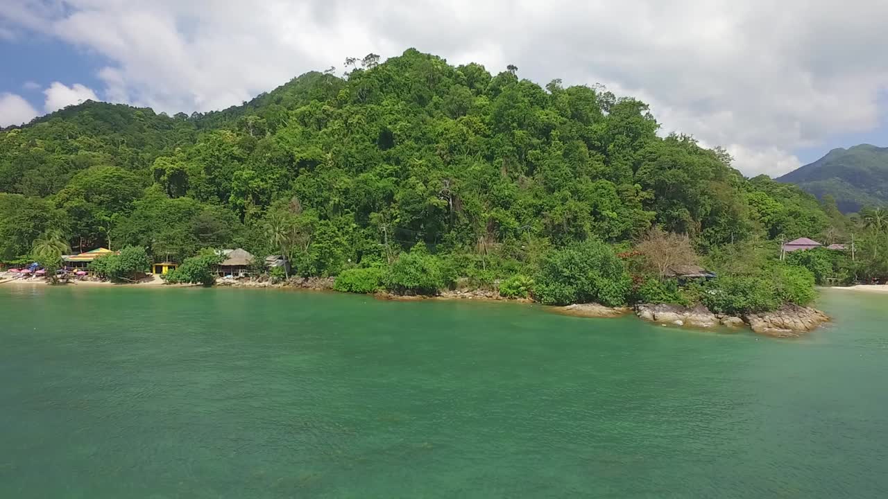 plataforma rodante lateral aérea de una pequeña playa y costa rocosa en koh chang con pequeñas casas de huéspedes y selva y océano