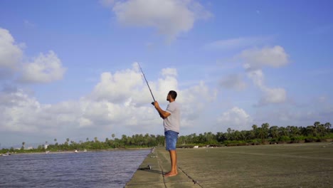 niño pescando en la playa a cámara lenta con una caña de pescar