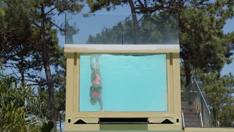 girl diving in a transparent pool container