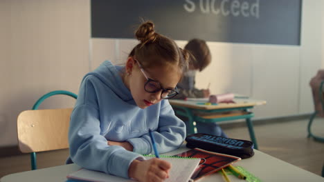 focused student schooling in classroom. diligent pupil writing in notebook