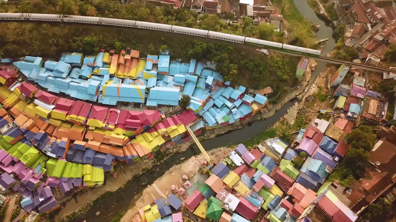 toma de un dron de un colorido pueblo en indonesia con un tren pasando