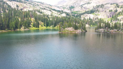 un drone aérien révèle un magnifique lac de montagne rocheuse avec de l'eau bleue claire et un sommet de montagne dans le colorado nederland entouré d'une épaisse forêt de pins