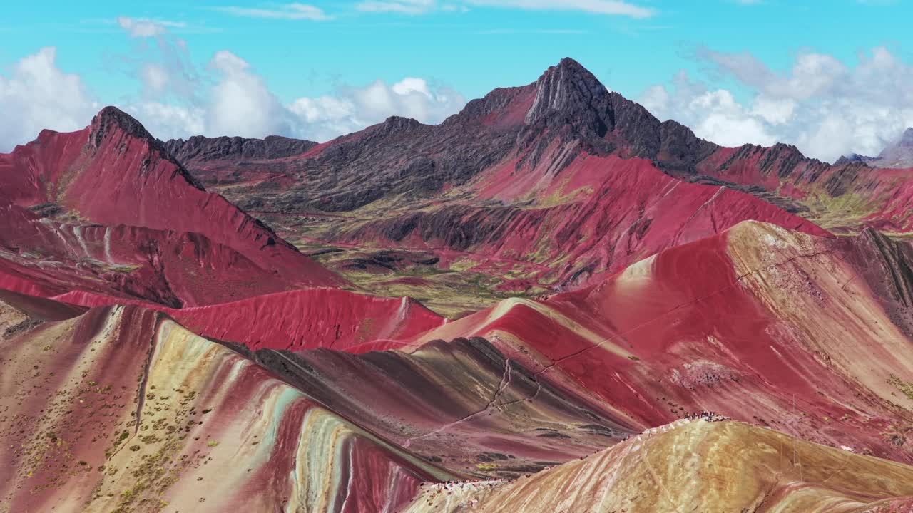 Rainbow Mountain Vinicunca Peru Perú aerial drone morning blue sky Montaña de Siete Colores Palccoyo clouds Peruvian Andes Red Valley striped hills seven colored Cusco Region parallax backwards pan up