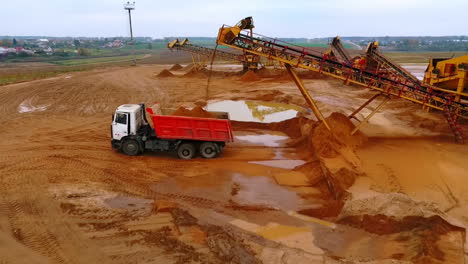 vista de avión no tripulado del transportador de minería verter arena en el camión volcador. maquinaria de minería