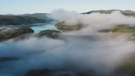 thin morning fog hangs above the valley and the lake dam