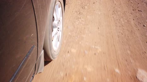 close up of a car wheel driving on a sand gravel road