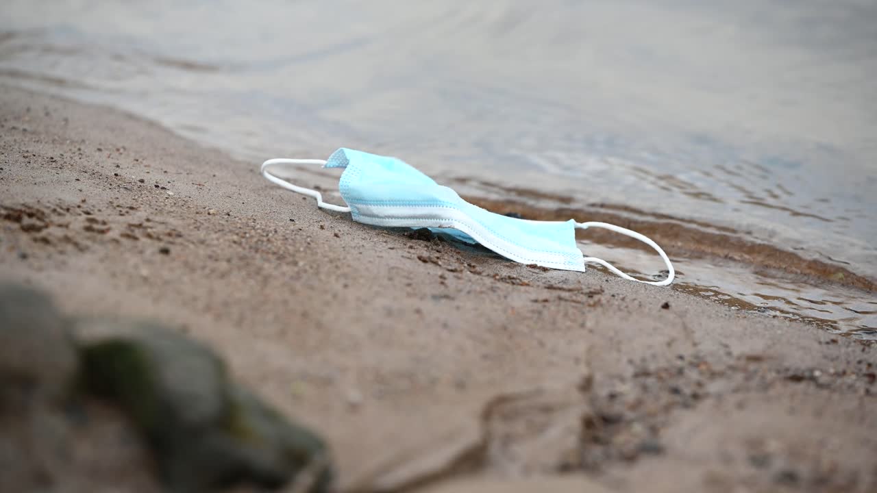 강둑에 버려진 더러운 외과용 안면 마스크